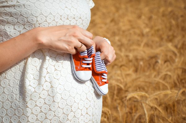 une femme enceinte tient des chaussures pour bébé sur son ventre, un test de paternité prénatal