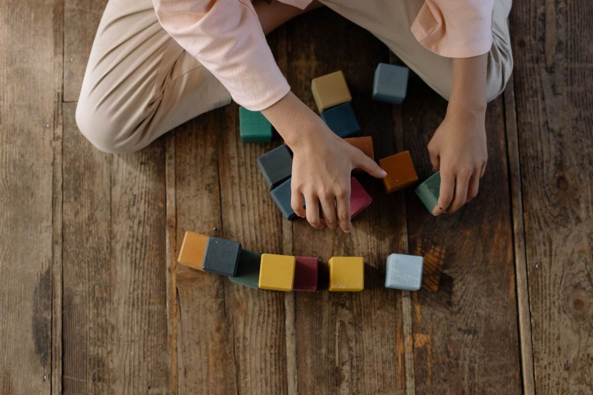 Personne jouant avec des blocs de construction colorés sur le sol