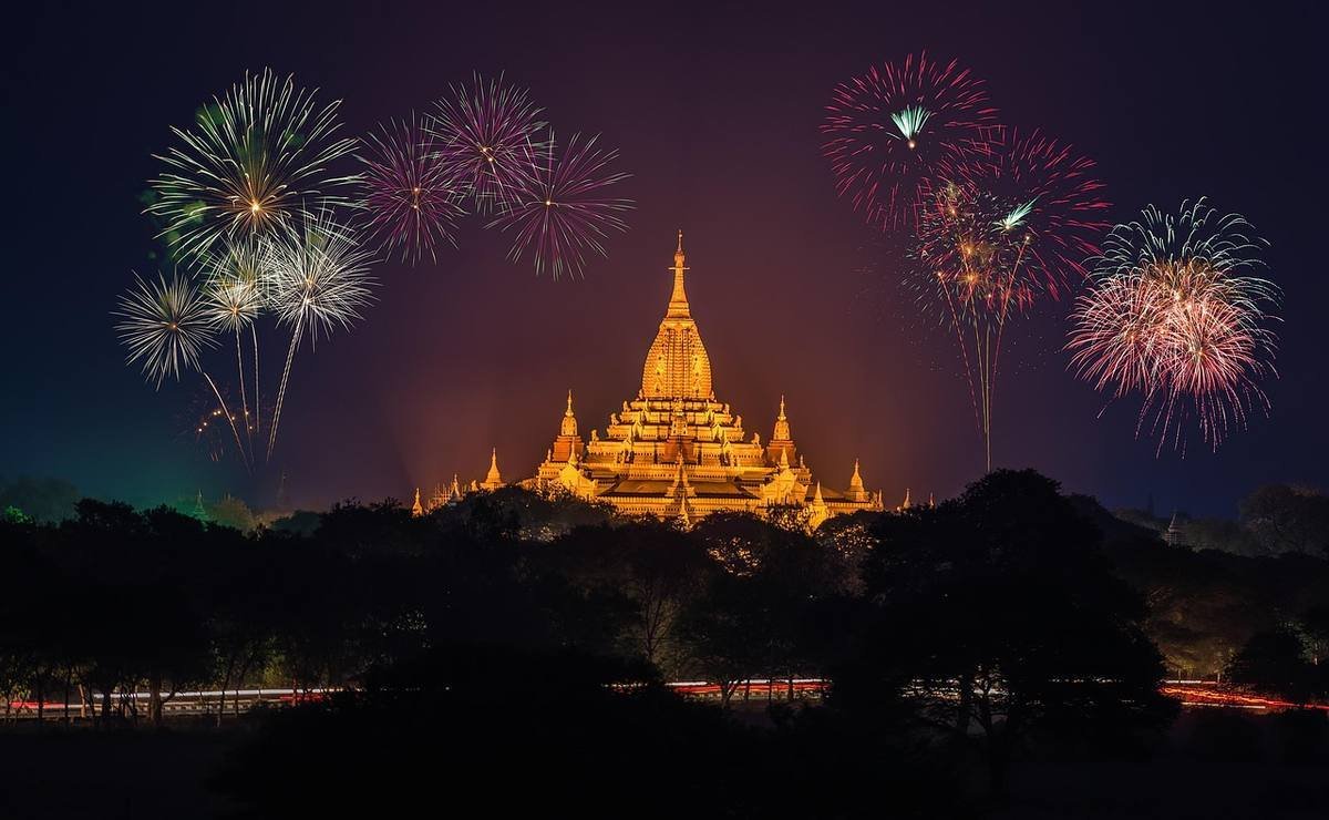 Temple bouddhiste doré illuminé la nuit avec feux d'artifice colorés Temple bouddhiste doré illuminé la nuit avec feux d'artifice colorés