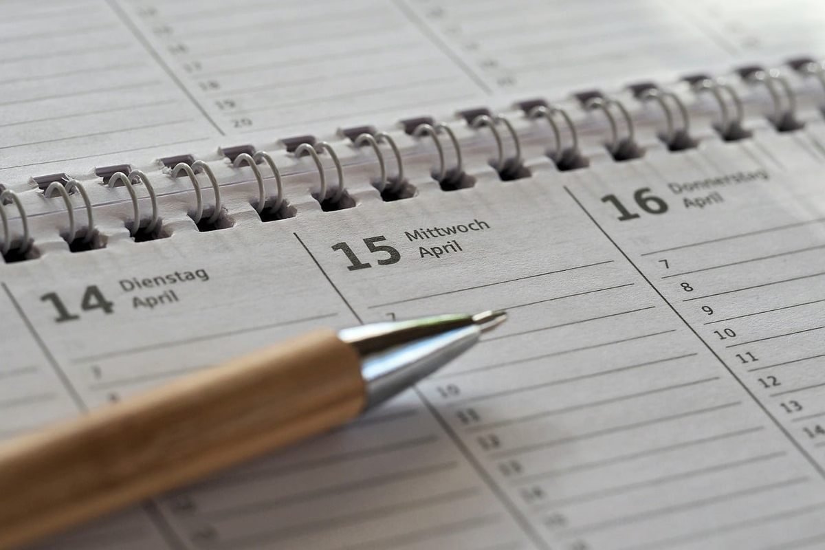 Calendrier ouvert en spirale affichant les dates 14, 15, 16 avril avec un stylo posé dessus Calendrier ouvert en spirale affichant les dates 14, 15, 16 avril avec un stylo posé dessus
