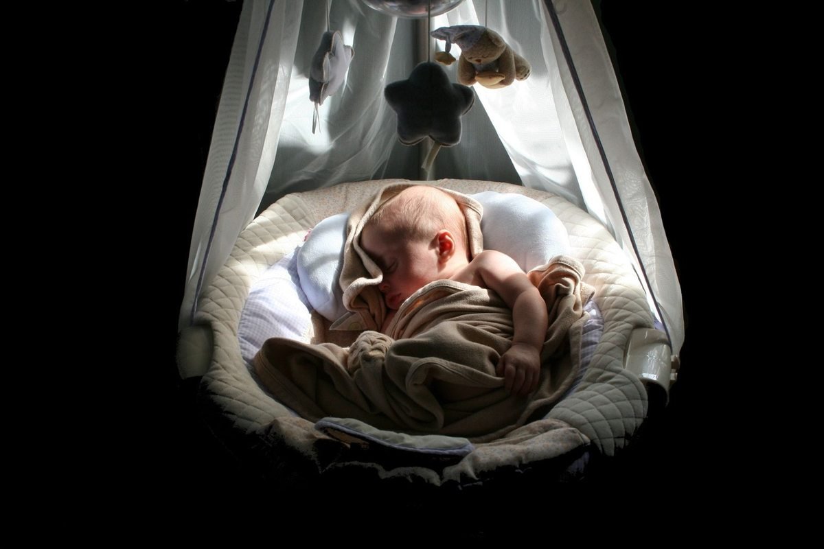 Bébé endormi dans un hamac avec jouets et draps, lumière douce Bébé endormi dans un hamac avec jouets et draps, lumière douce
