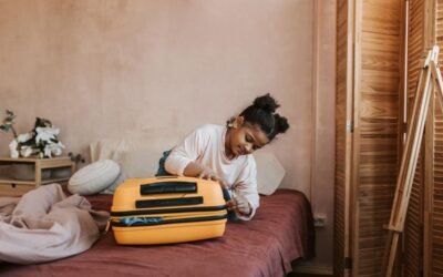 Une jeune fille emballe une valise jaune sur un lit